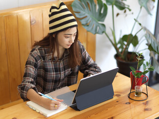 Female teenager preparing for hear exam with stationery and tablet in cafe