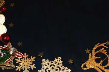 Gold snowflakes, deer, bells and stars and red balls on a dark blue background. Christmas background.