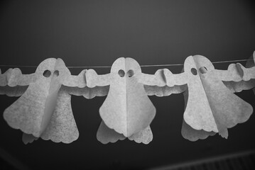 Halloween decorarion. Concept DIY and children creativity. Step-by-step instructions: making garland of ghosts from white and black paper. Step 3 child throughout rope from paper ghost