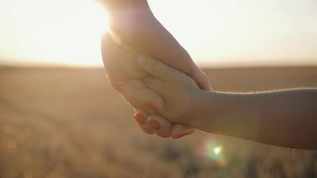 Mother and little son holding hands into the sunset. Child have a trust for mother, family concept.