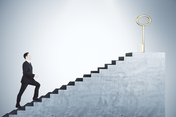 Young businessman climbing stairs with golden key