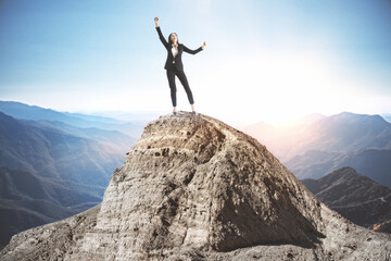 Happy businesswoman standing on mountain top.