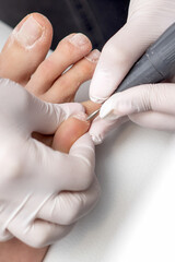 Process of professional pedicure. Pedicurist uses electric nail machine while doing pedicure on toes