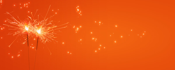 zwei brennden Wunderkerzen vor leuchtendem orange hintergrund, abstraktes modernes party konzept banner mit freiem textraum - obrazy, fototapety, plakaty