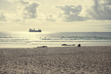 Obraz premium Sandy beach with container ship silhouette in the sea horizon