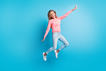 Fototapeta na wymiar Photo portrait of girl jumping up making plane with hands isolated on pastel blue colored background