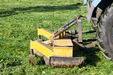 Fototapeta na wymiar close up of tractor mows grass on lawn in city yard