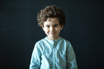 portrait of a curly boy on a dark background