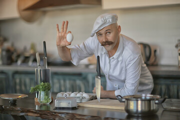 Fototapeta na wymiar french chef in the kitchen preparing food, cooking, haute cuisine, man with mustache