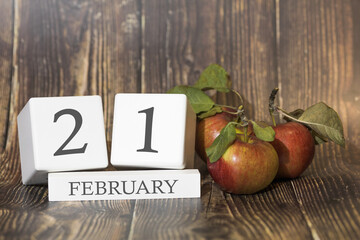 February 21. Day 21 of month. Calendar cube on wooden background with red apples, concept of business and an important event. Winter season.