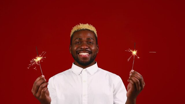 african american man holding a burning stick of dynamite in studio red background