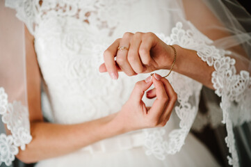Girl put a bracelet on arm. bride putting on jewelry, focus on bracelet. Bridal preparation for the wedding ceremony.