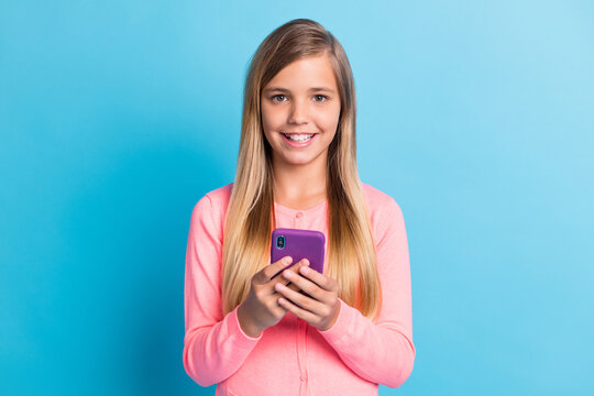 Photo portrait of girl smiling holding purple phone in two hands isolated on pastel blue colored background