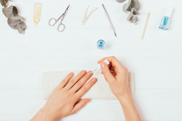 Female hands apply nail polish next to self-manicure accessories