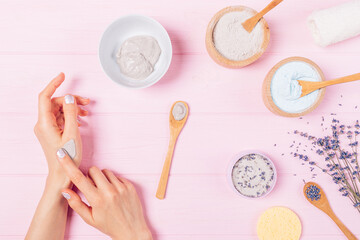 Flat lay arrangement woman's hands apply homemade cosmetic clay mask