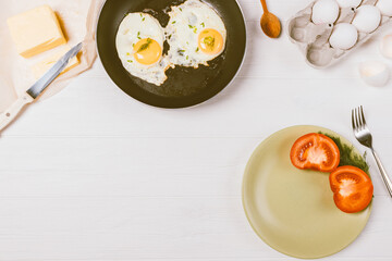 Healthy breakfast of fried eggs, fresh vegetables on white kitchen table