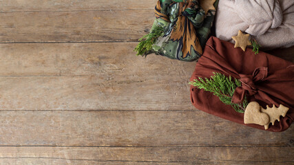 Christmas gift packed furoshiki lie on a brown wooden table. zero waste concept