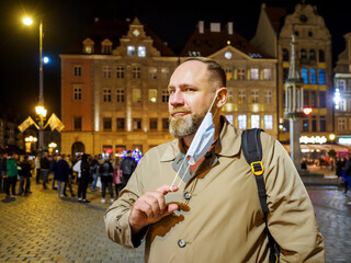Adult man wearing mask walking in a night european city. Mask is a necessary thing in new normal...