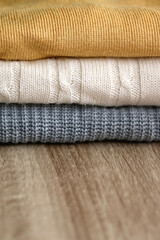 Stack of sweaters on wooden table. Selective focus.