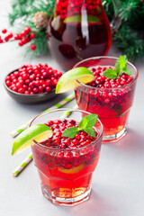 Lingonberry and lime punch or limeade in glass, christmas tree decoration on background, vertical
