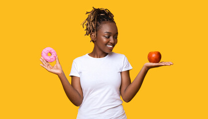 Slim black woman looking at apple in her hand