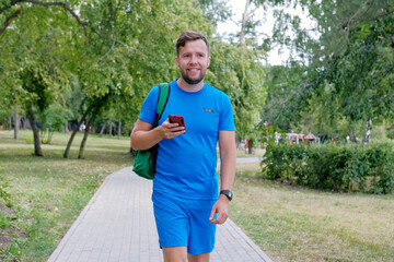 Attractive runner in blue sportswear using smartphone checking fitness results.