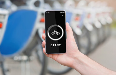 Modern outdoor workout with technology and bicycle trip. Hand holds phone with start button and bike on screen