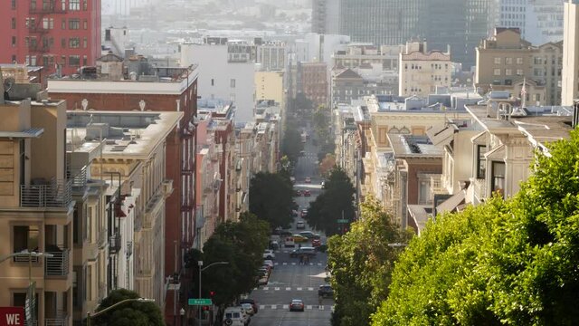 Iconic hilly street and crossroads in San Francisco, Northern California, USA. Steep downhill road and pedestrian walkway. Downtown real estate, victorian townhouses abd other residential buildings.
