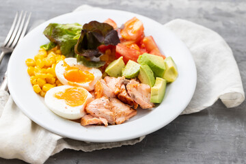 salad salmon with vegetables and boiled egg on white plate on ceramic background