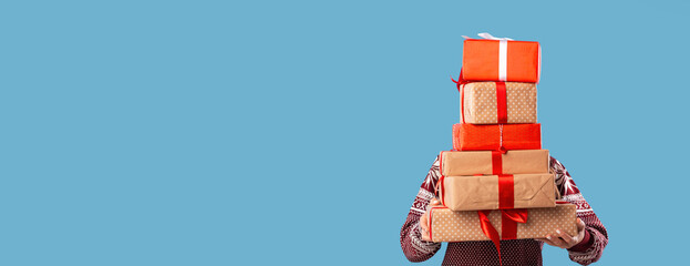 Faceless millennial lady carrying pile of wrapped Christmas gifts on blue background, banner design...