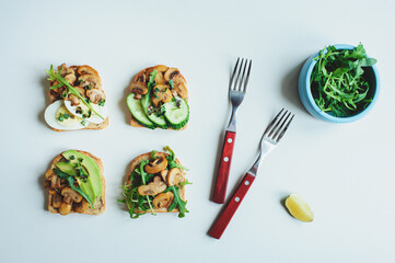 various morning vegetarian toast set with mushrooms, avocado, arugula, cucumber and eggs. Healthy food on white background