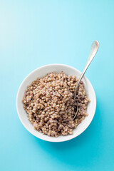 boiled buchwheat in white bowl on blue background