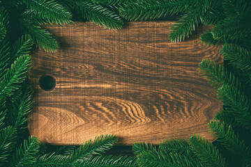 Top view of wooden plate decorated with fir tree branches. New Year dinner concept with empty space for your design