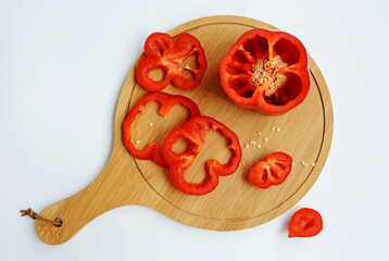 Sliced red bell pepper lies on a board on a white background