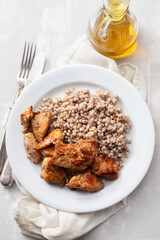 boiled buchwheat with chicken in sauce on white plate