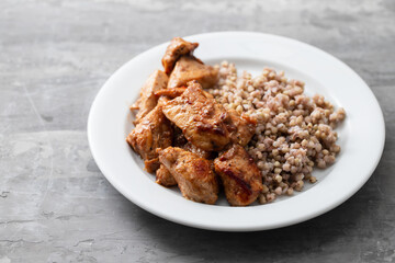 boiled buchwheat with chicken in sauce on white plate