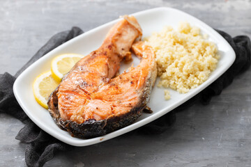 fried salmon with cous cous and lemon on white dish