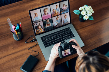 Female photographer working on photos on laptop and camera. Woman editing retouching browsing photos working as a freelancer sitting at desk