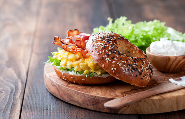 Bagel sandwich with scrambled eggs, bacon and cream cheese, selective focus