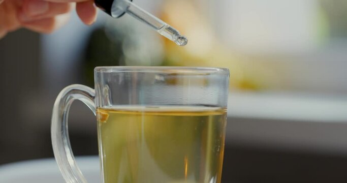 dietary supplements and vitamins - adding drops in cup of tea with dropper