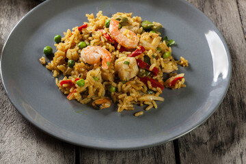 Traditional seafood paella with shrimp, fish and chicken seved in plate.