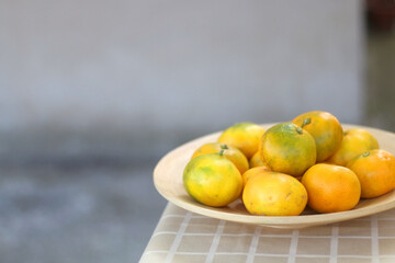 Wooden bowl with tangerines on a table. Selective focus.