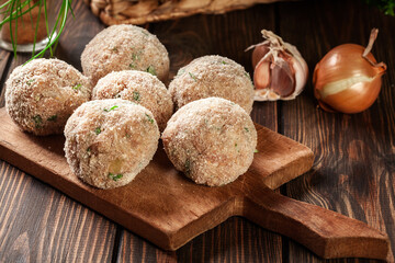 Raw meatballs rolled in a crispy bun prepared for baking