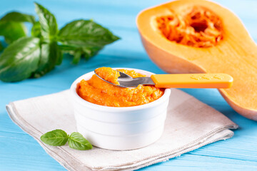 Organic pumpkin puree with spoon on a blue wooden table.