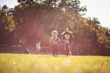 Plakat Two kids in Halloween suits running trough nature.