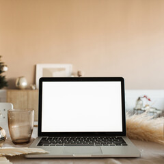 Blank display screen laptop computer on table with beautiful decorations. Modern cozy comfortable home living room interior design. Home office desk workspace. Mock up copy space.