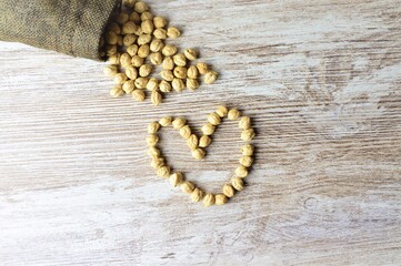 Chickpeas, vegetables very beneficial for the body, on a wooden table in the shape of a heart.