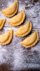 Homemade dumplings, vareniki on an old wooden table, sprinkled with flour, space for text