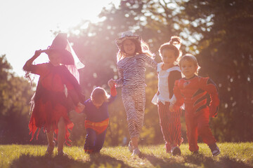 Obraz na płótnie Canvas Happy kids running trough park in the Halloween suits.
