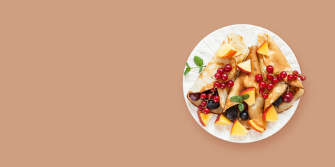 Pancakes or crepes with berries in a plate on color background. top view
